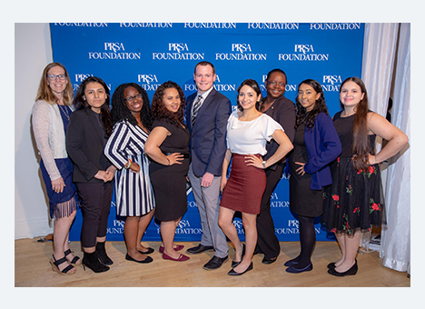 Foundation Members smiling at the camera in front of a banner that reads 